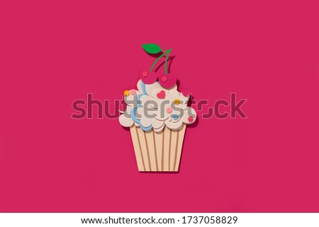 Handmade paper cut out cupcake with cherry. On pink background. 