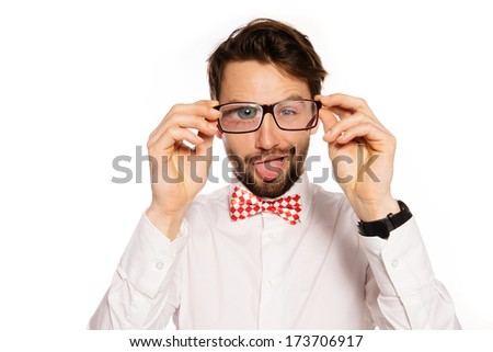 Humorous portrait of a goofy young businessman wearing glasses squinting and sticking out his tongue in a playful gesture, isolated on white