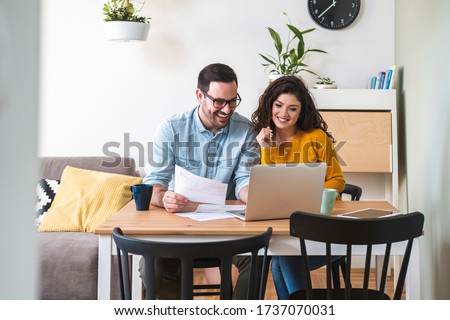 Happy husband and wife read good news online at laptop, smiling man holding documents receiving positive decision from bank, man and woman get email having mortgage or loan approved stock photo  Royalty-Free Stock Photo #1737070031