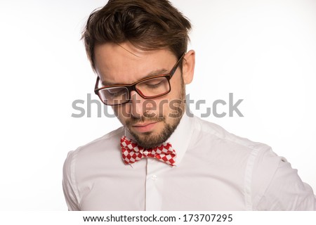 Old-fashioned nerdy businessman wearing a red and white polka dot bow tie looking over the top of his glasses , isolated on white