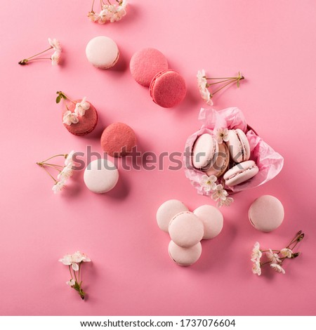 Roze macaroons in gift box and Cherry blossoms. Sweet macarons present on pink background with copy space. Top view. Holiday time concept