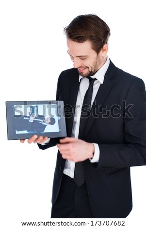 Handsome young businessman displaying a handheld tablet computer showing an image of himself to the viewer, isolated on white