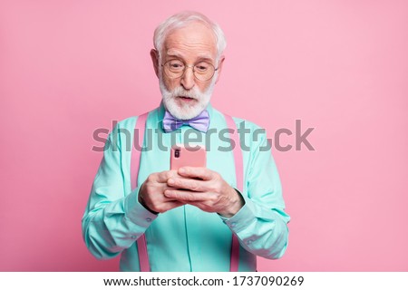 Photo of cool stylish grandpa holding telephone hands read email freelancer good news wear specs mint shirt suspenders violet bow tie pants isolated pink pastel color background