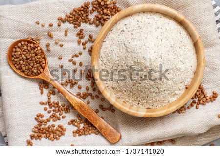 Buckwheat flour in a bowl buckwheat grain on a napkin top view  Royalty-Free Stock Photo #1737141020