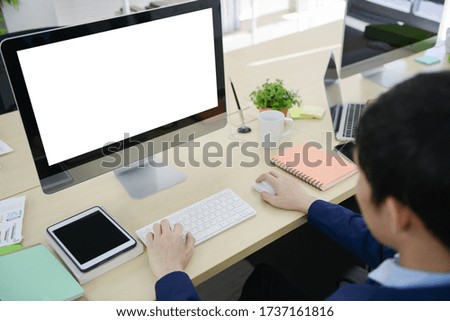 Mock up white screen of computer display with businessman working on the office desk