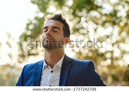 Young businessman taking a deep breath while standing with his eyes closed outside during a break from work Royalty-Free Stock Photo #1737242708
