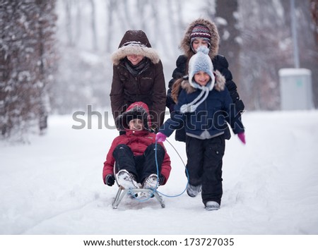 Happy three kids and their mother walking in winter park
