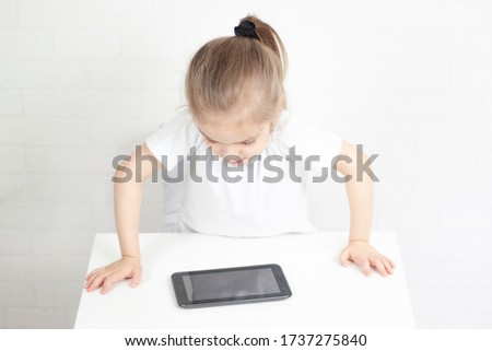 Beautiful little girl looking at the screen of a tablet computer. Selective focus