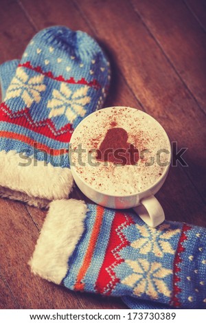 Gloves and cup with coffee and shape of the cacao heart on it. Photo with vintage style