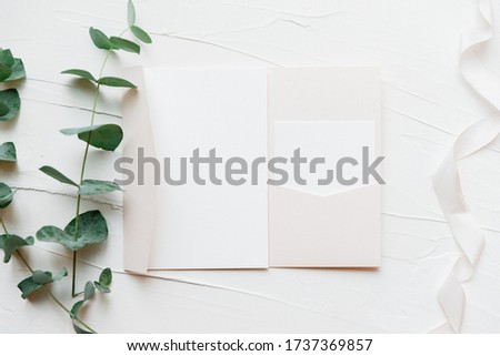 White paper on the table with side petals of greenery.