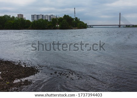 Landscape photo of the city. View of the river, the opposite shore with houses and a bridge.