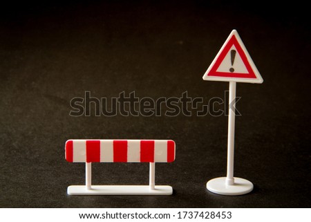 Road sign, plastic road warning sign with an exclamation mark and fence, on a black background.