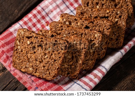 against a dark background fresh whole-grain dark bread sliced ​​and neatly laid out on a red cloth. nutritious, healthy product consisting of grains and dried fruits for a healthy and tasty lifestyle.