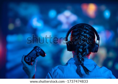 Gaming, a girl plays a game on the big screen. With a gamepad and joystick. Neon light. Gaming streams, vlogs