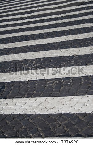 Detail of zebra striped pedestrian walk on cobblestone street