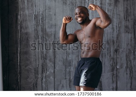 African bare-chested boxer rejoices in victory and shows biceps.