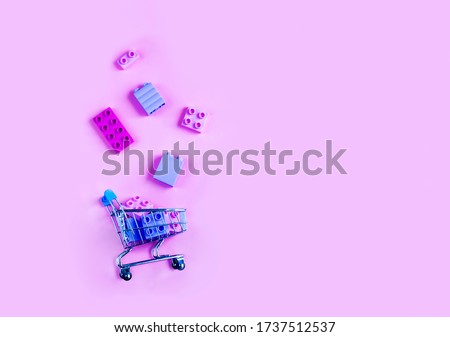 Toy shopping cart with children's constructor over pink background. Copy space for text or design. Monochrome concept of sale, discount and advertisement. Copy space for advertisement. Royalty-Free Stock Photo #1737512537