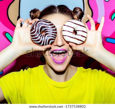 Young pretty woman with sweet multicolored makeup on the pink donat background closeup.