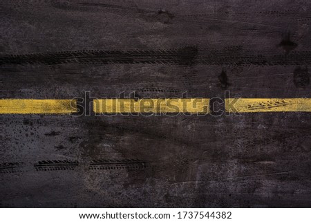 Imitation of asphalt road surface with traces of car tires and stripes of yellow markings in grunge style