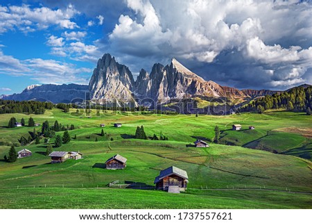 Alpe di Siusi - Seiser Alm with Sassolungo - Langkofel mountain group in background at sunset.  Wooden chalets in Dolomites, Trentino Alto Adige, South Tyrol, Italy