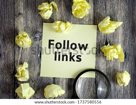 Follow links - text on yellow note sheets on a dark wooden background with crumpled sheets and a magnifying glass