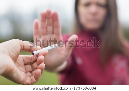 girl refuses a cigarette. woman quits smoking. bad habit.  World No Tobacco Day. human arm is gesturing with refusal. antismoking concept Royalty-Free Stock Photo #1737596084