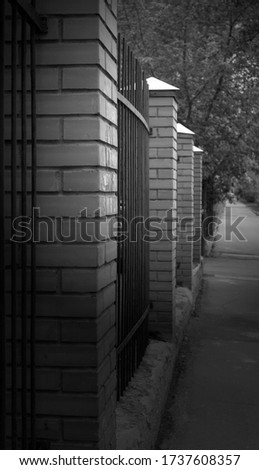 Metal fence, brick columns. Protections of buildings, parks. Black and white photography