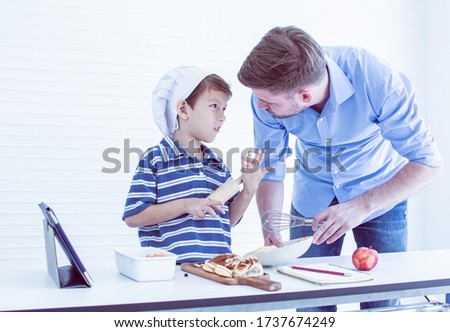 Caucasian handsome father is teaching his son to cook for breakfast in kitchen