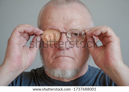 Elderly man in glases with Occluder. Ortopad Man Eye Patces nozzle for glasses for treating strabismus (lazy eye).Senior with beards