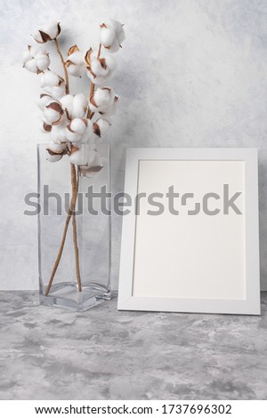 White frame with space, Mockup for design, with a vase and cotton. Light tender photo.