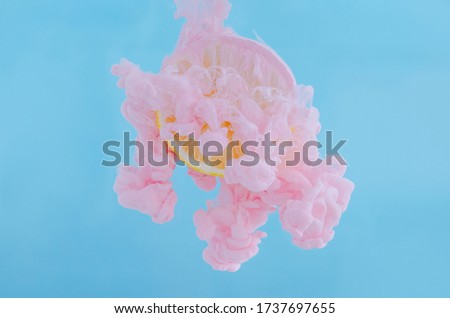 Slice lemon with partial focus of dissolving pink poster color in water on blue background for summer, abstract and background concept.