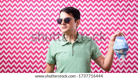 Young man wearing sunglasses leaving protective mask against coronavirus. New normallifestyle. Free man. Fashion Man ignoring protective mask against COVID-19. Social distancing.