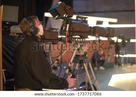 masked cameraman is filming a television show in the studio. TV