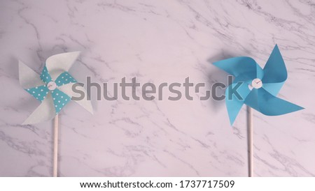 Wind wheel paper real toy on white color marble stone background which made from origami hand made on light blue colour japanese special material and wood stick for baby or kids playing.  
