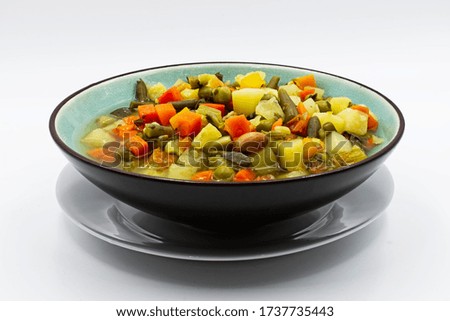 Homemade soup of various vegetables on a plate. White background