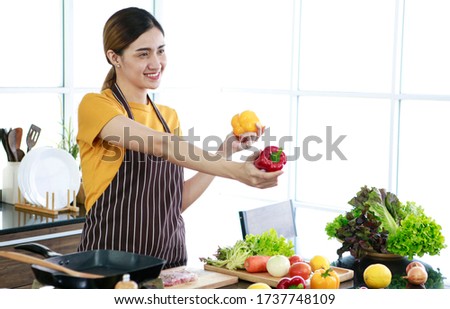 Asian women present fresh food. Housewife trying to cooking and showing tomato and chilli in kitchen in house to take picture for sell food box online. Work from home / Stay at home / covid19 concept 