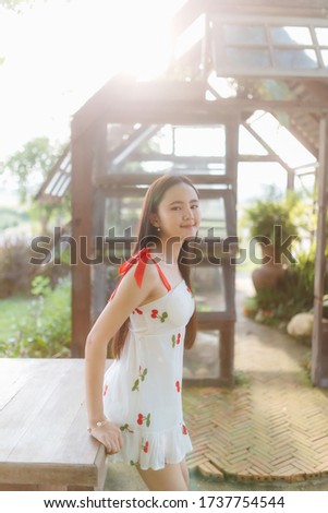 Beautiful Asian woman wear white dress sitting on wood table in garden.