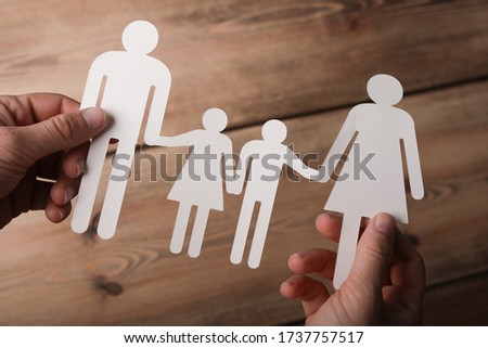 The paper cut of a family in the hands of a man with a wooden background