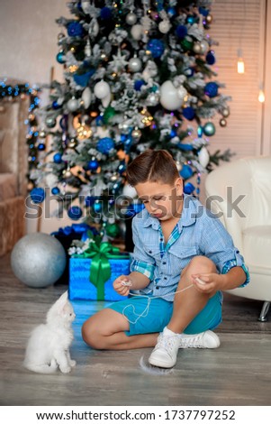 A beautiful boy in blue clothes is playing with white little kittens.