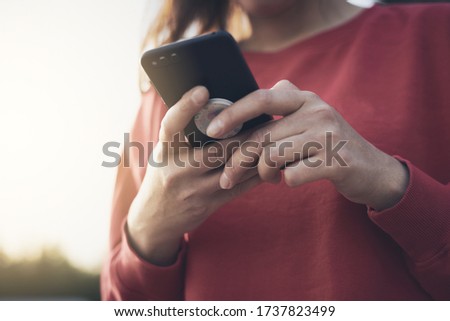 Girl holds a smartphone in her hands while standing on street and communicates on phone