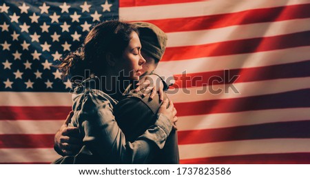 Independence day, memorial Day. A woman embraces a soldier. Couple on the background of the American flag. Copy space. The concept of American national holidays and patriotism