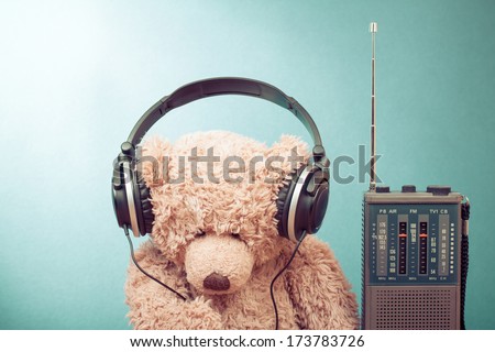 Retro toy Teddy Bear with headphones and radio receiver front mint green background