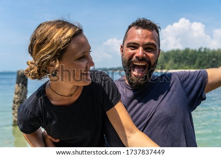 Stock photo of funny couple in a good time at the seashore. In the background you can see the sea and a beach with a jungle.