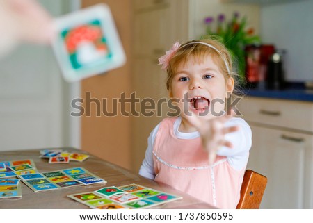 Adorable cute toddler girl playing picture card game. Happy healthy child training memory, thinking. Creative indoors leisure and education of kid during pandemic coronavirus covid quarantine disease