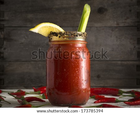 Bloody Mary or Bloody Ceasar with celery in mason jar rimmed with black pepper Royalty-Free Stock Photo #173785394