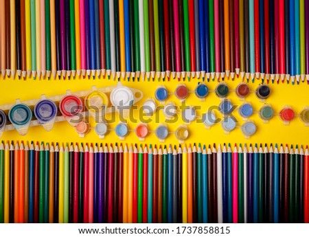 Back to school. School background. Color pencils and paint on yellow background. Close up. Top view, layout, flatly