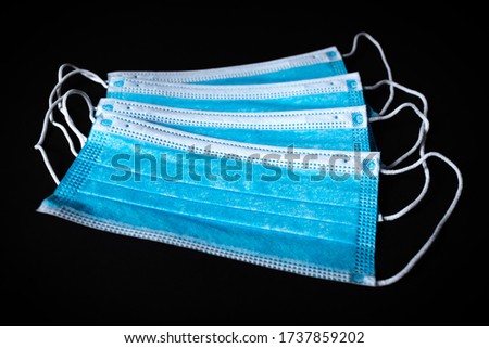 Four Surgical Face Masks lying on top of each in black background Royalty-Free Stock Photo #1737859202