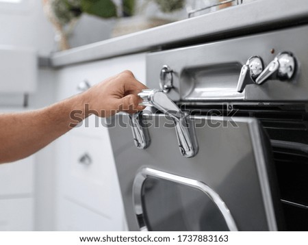 Man using modern oven in kitchen, closeup