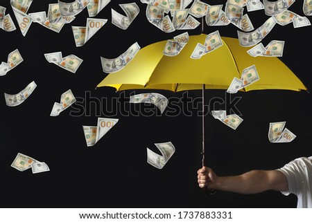 Man holding yellow umbrella under money rain on black background, closeup 