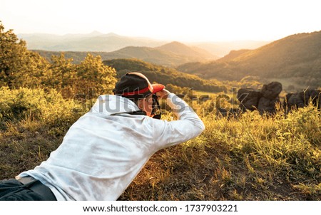 Man photographer with and camera taking photo of sunset mountains. Travel Lifestyle. Hipster guy taking photo of landscape and dry surface explore wild nature. Adventure active vacations outdoor
